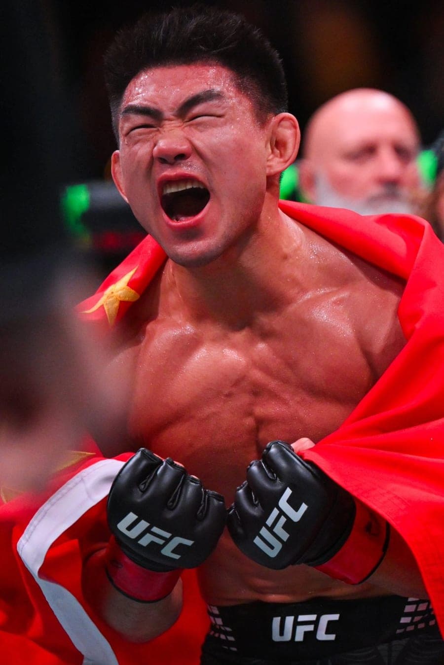 Song Yadong roaring in the octagon with a national flag over his shoulders