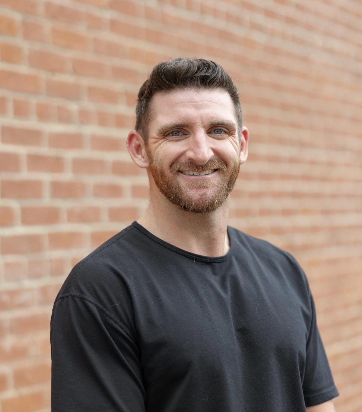 Portrait of Dr. Charlie Brennan against a brick wall